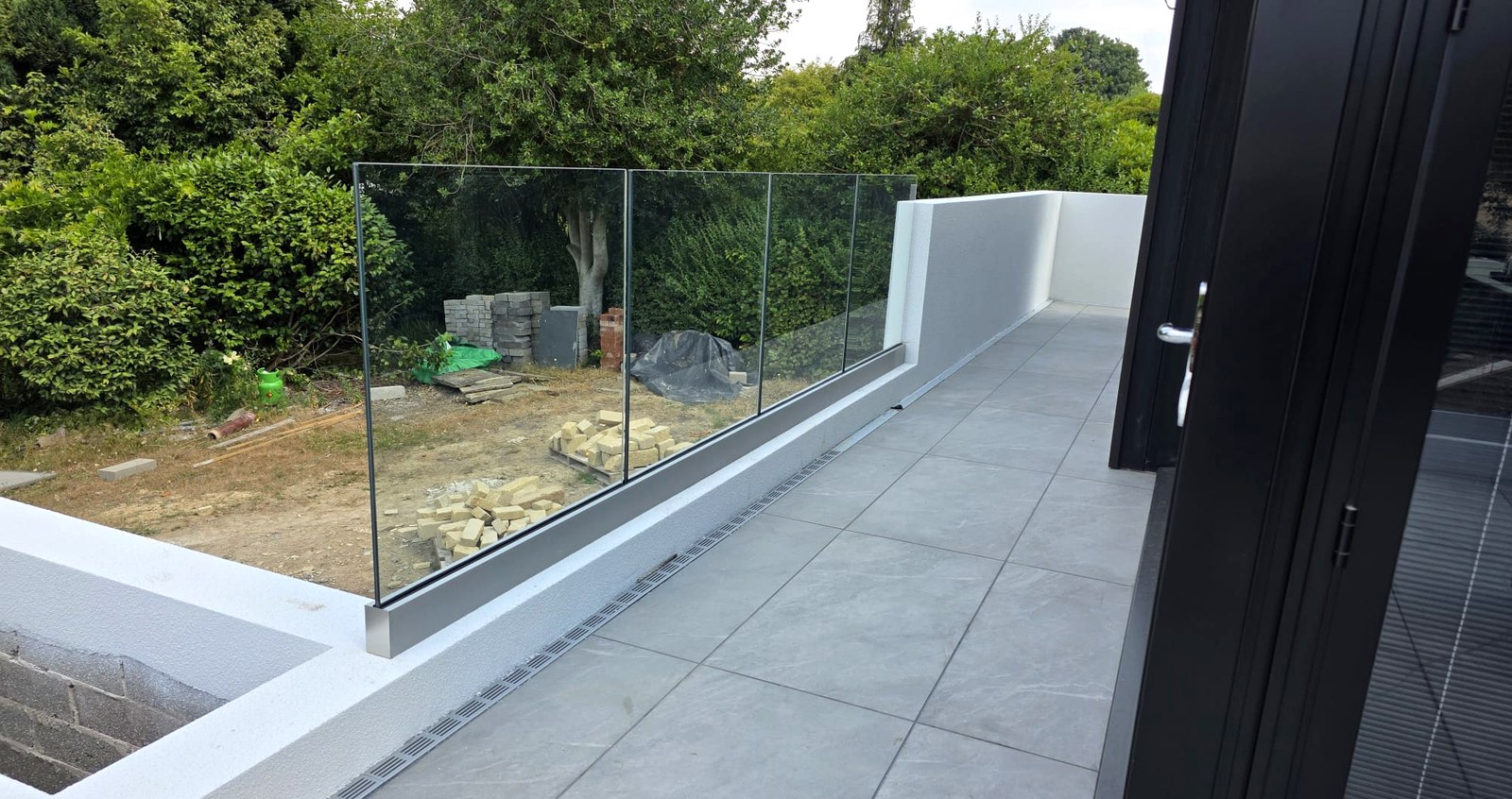 Frameless glass balustrade in a satin aluminium base channel along a raised patio edge, Wombwell, Barnsley